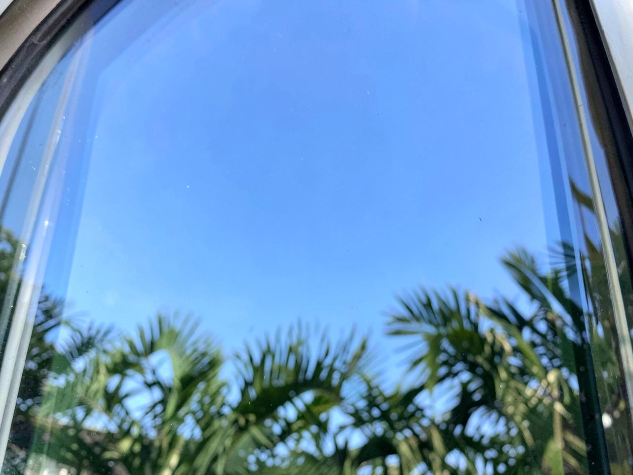 Spotless streak-free window glass reflecting blue sky and palms